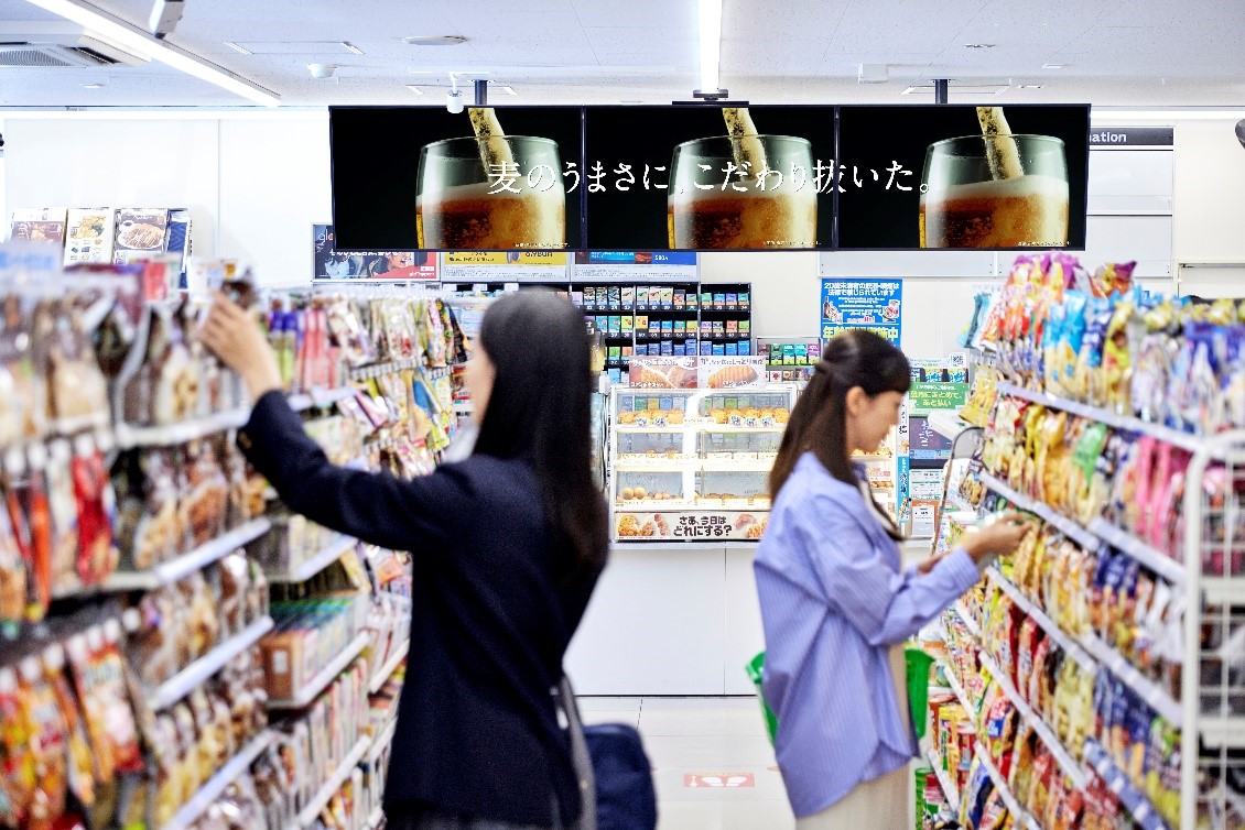 写真：FamilyMart店内で買い物する２名の女性とサイネージ画面